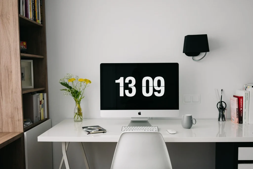 A desk featuring a computer and a decorative vase, creating a functional and aesthetic workspace.