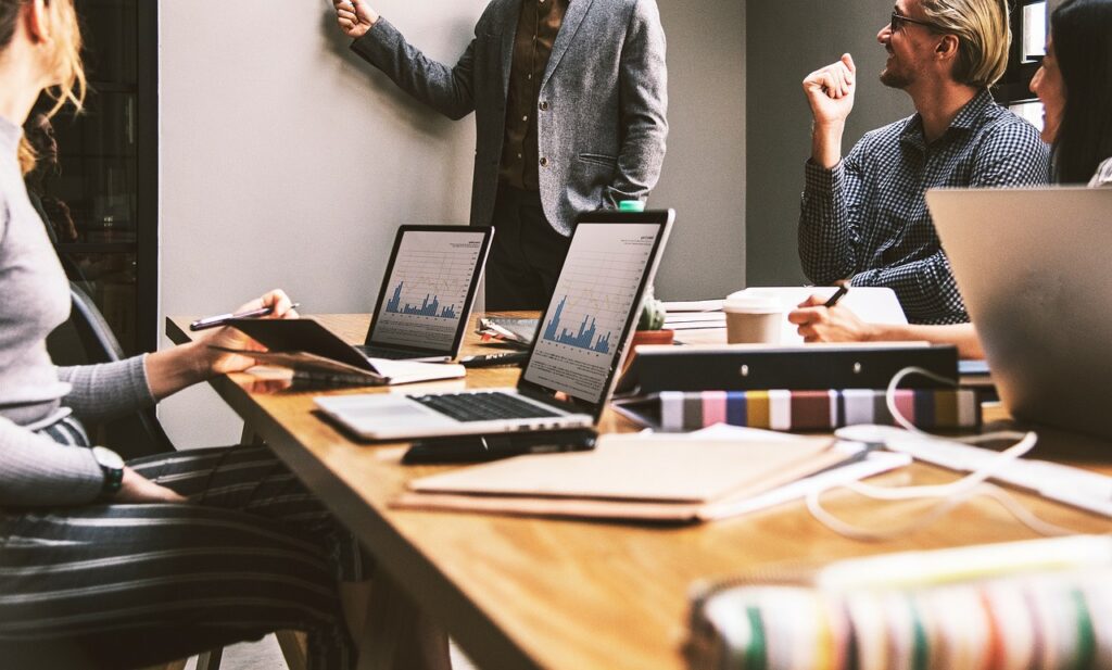 A diverse group of individuals collaborating around a table, each engaged with their laptops in a productive environment.