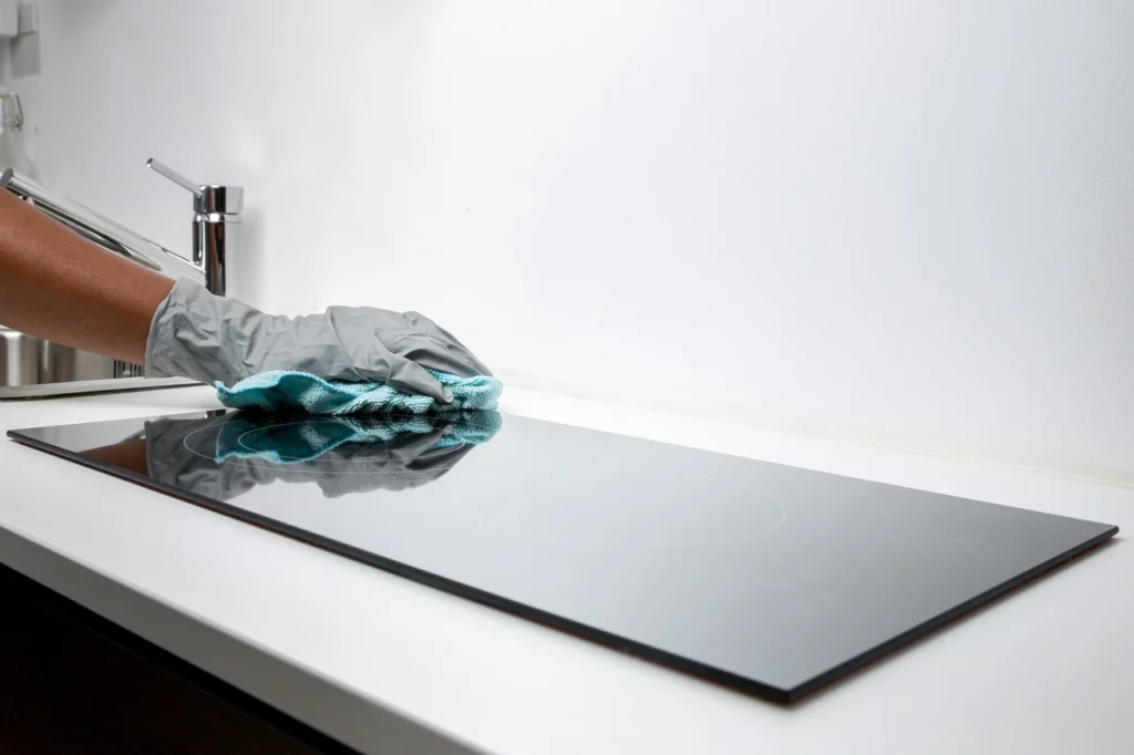 A person in gloves meticulously cleans a glass countertop, ensuring a spotless and shiny surface.