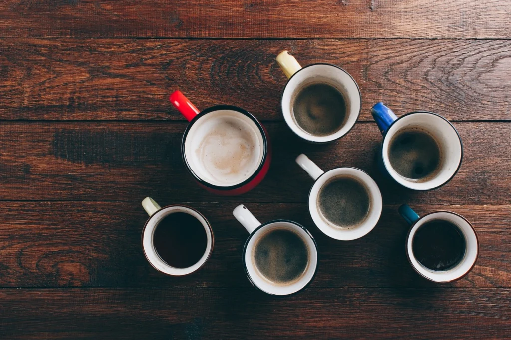 Five coffee cups arranged on a rustic wooden table, showcasing a warm and inviting atmosphere.