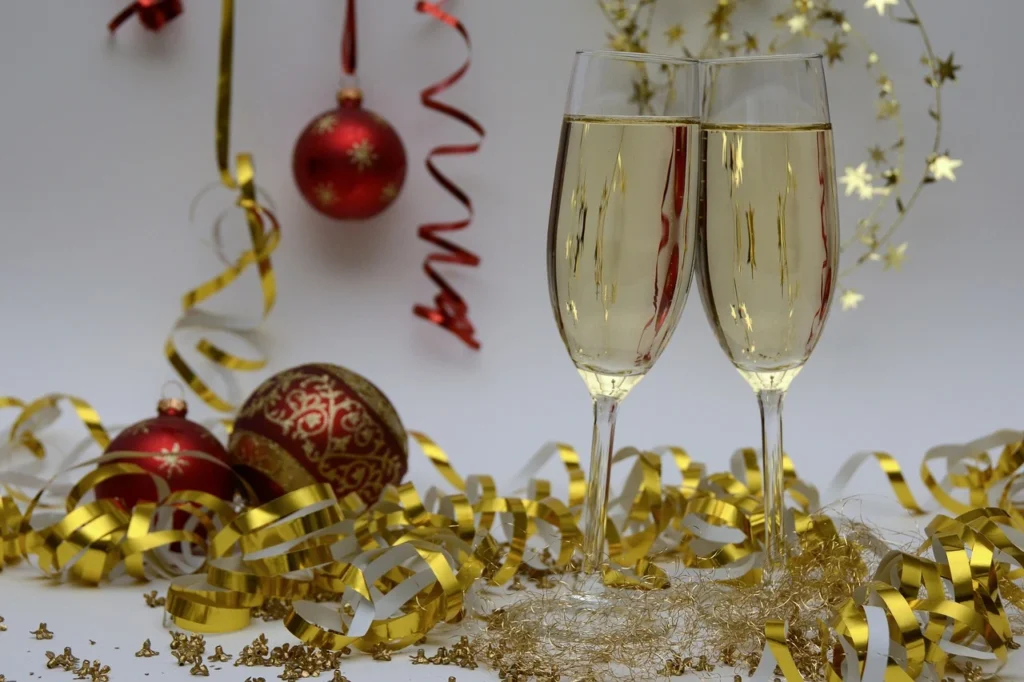 Two elegant champagne flutes adorned with festive Christmas decorations, symbolizing celebration and holiday cheer.